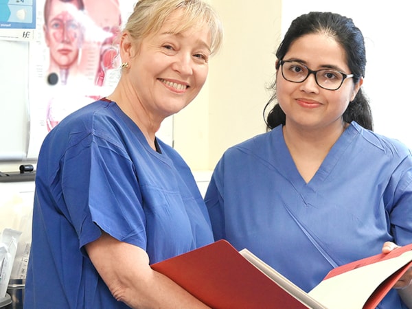 Two nurses eye and ear hospital in clinical setting smiling at camera